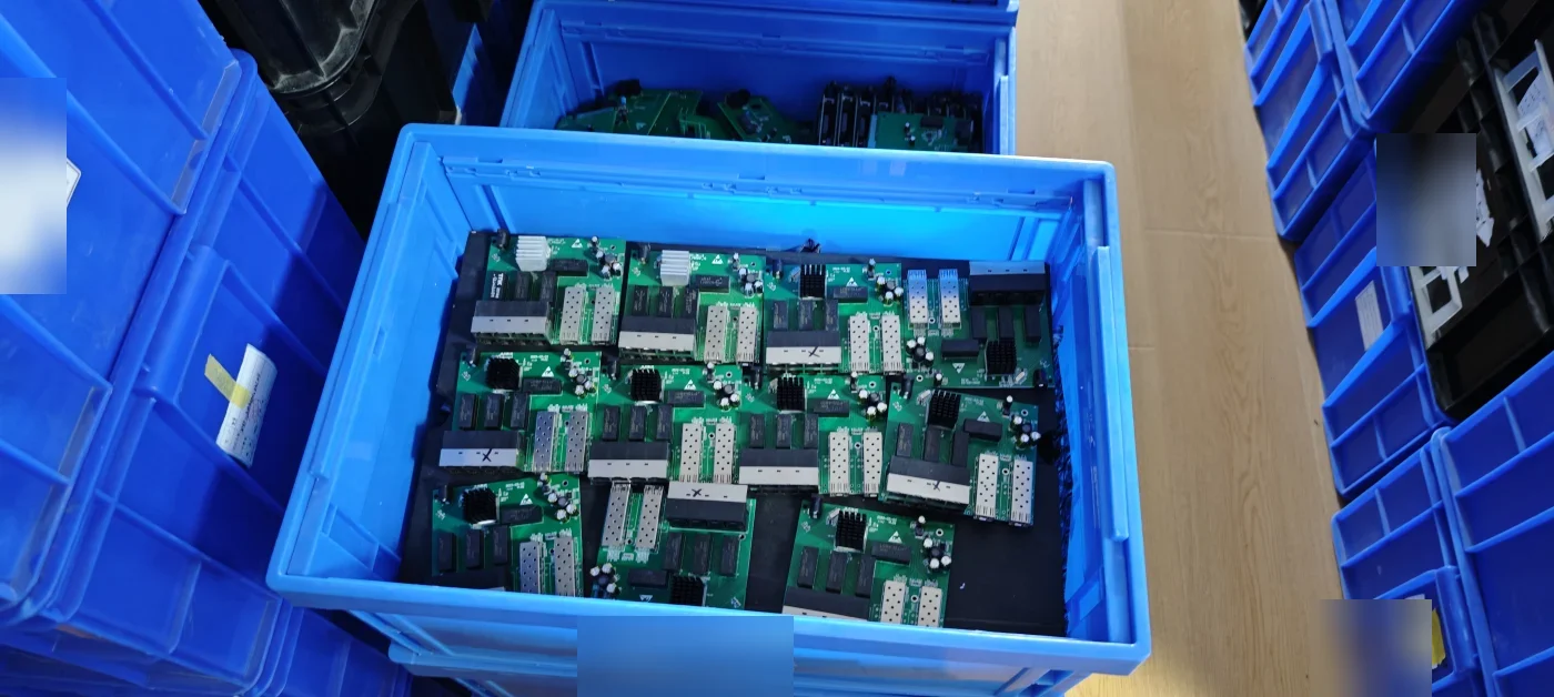 PoE switch PCBA boards with SFP cages staged in crates at the factory for a Pakistan order